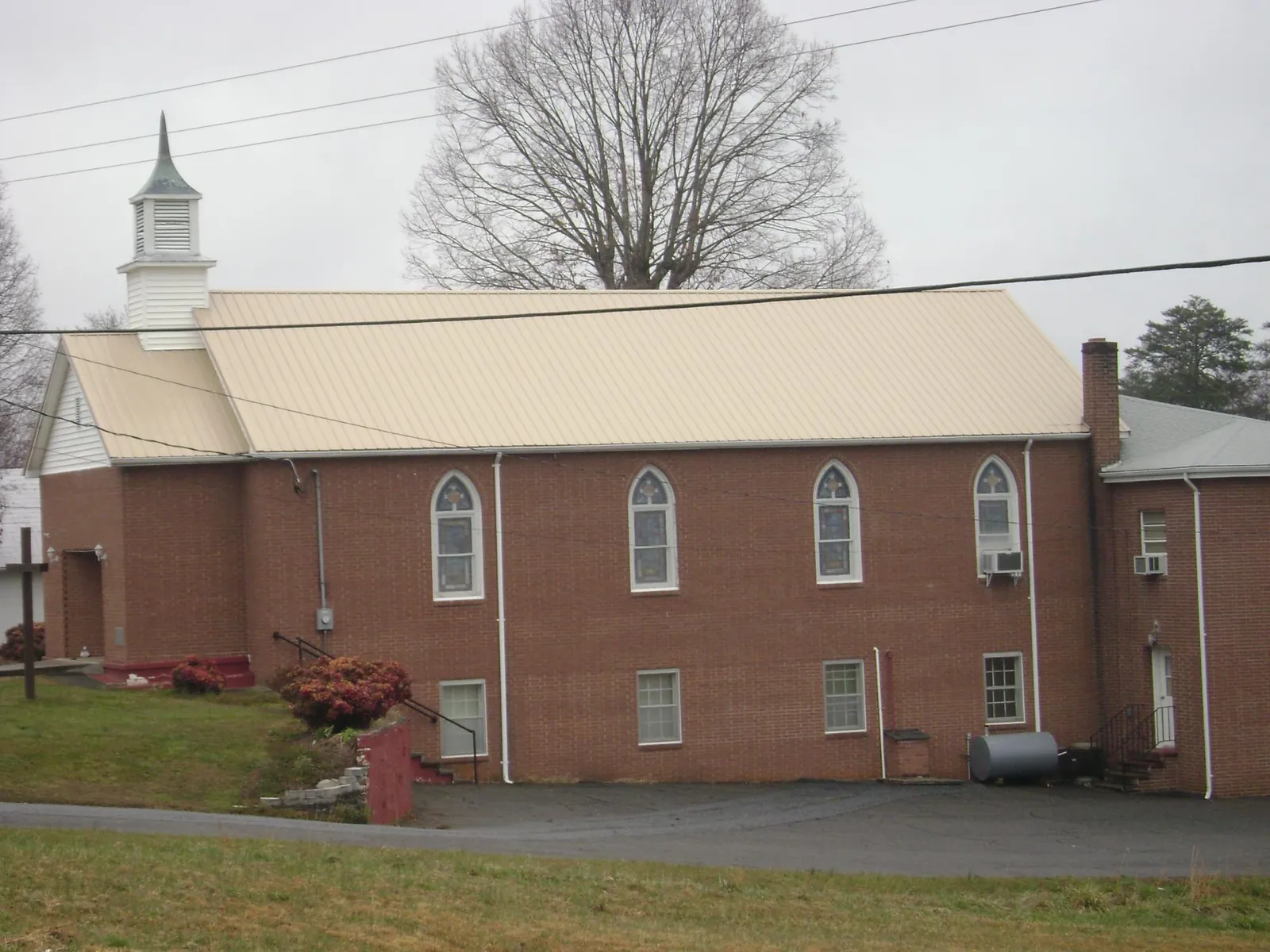 New tan metal roof on a brick church with a white steeple in Fort Dodge