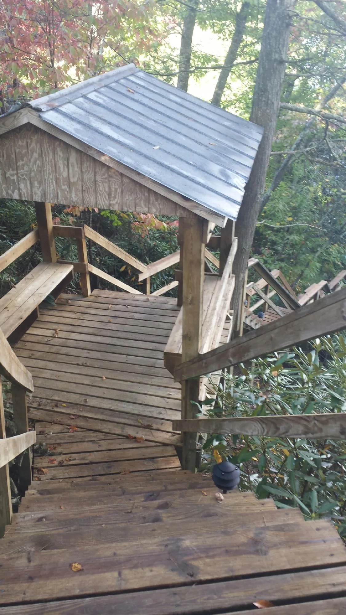 Metal roofed shelter over wooden steps on a wooded walkway — Skylight Repair & Installation work by our crew in Fort Dodge
